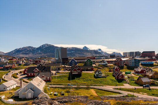 View of colorful houses and modern buildings against a backdrop of snow-capped mountains and a clear blue sky in Nuuk, Sermersooq, Greenland.