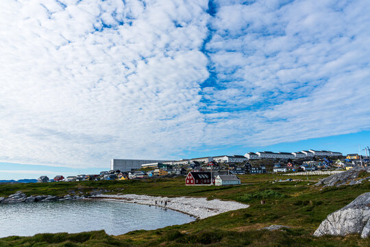 View of the colorful houses and rocky coastline under a dramatic cloudy sky in Nuuk, Sermersooq Municipality, Greenland.