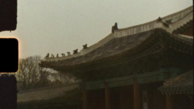 Super 8 mm vintage film of architecture showing rooftop temple building and a tree in the background in the courtyard grounds of Changdeokgung Palace shrine in Seoul city South Korea culture tourism