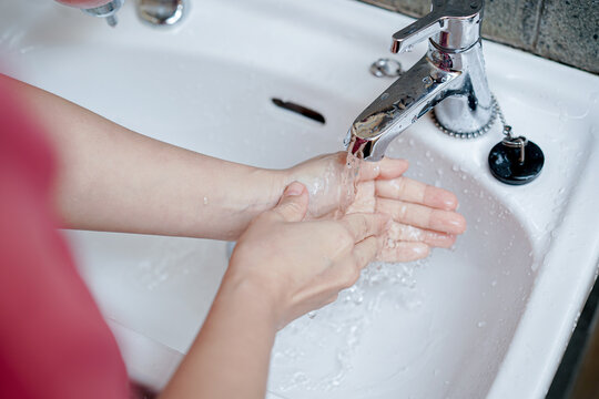 Close up of woman rinsing wrists and hands under running tap water