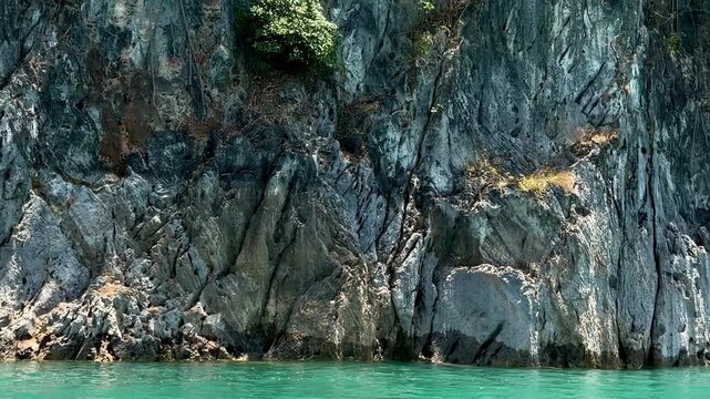 Close-up of massive vertical limestone cliffs and turquoise water at Cheow Lan Lake. Ancient rock formations and prehistoric mountain textures in Khao Sok National Park, Southern Thailand.