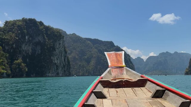 Epic view from a traditional boat of the gigantic Avatar-like limestone cliffs at Cheow Lan Lake. Towering mountain peaks rising from emerald river waters in Khao Sok National Park, Thailand.