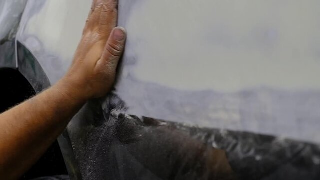Car polishing process in auto repair shop, worker using orbital sander on vehicle body