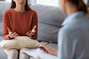 Obraz premium Woman sits on sofa and speaks with her psychologist while professional takes notes during mental health therapy session High quality photo