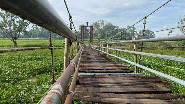 Rustic Suspension Bridge Over Water with Wooden Structure and Scenic Natural Landscape View
