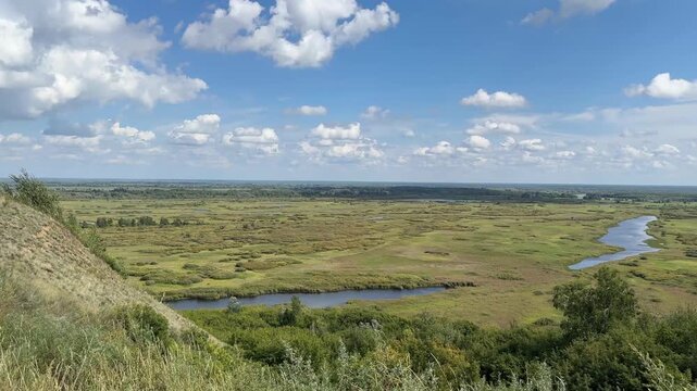 Aerial panoramic view of vast Siberian floodplain wetlands with winding river, oxbow lakes, marshes and endless green meadows in summer