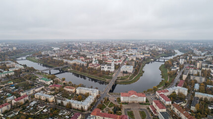 Obraz premium Aerial view of a city with rivers and bridges on a cloudy day, showcasing urban development and natural waterways.