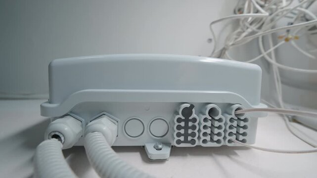Optical Network Distribution Box Mounted on Wall with Cable Conduits and Wire Connectors | Fiber Optic Telecommunications Equipment | Indoor Network Infrastructure. Bottom-Up View