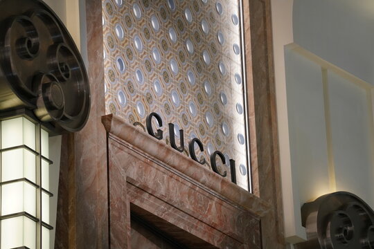 A luxury Gucci brand sign on a marble boutique storefront.