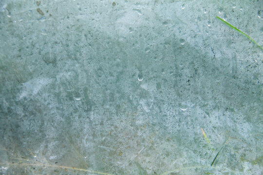 A captivating macro photograph featuring natural morning dew droplets and condensation collected on the surface of a sheet of clear plastic. The image captures the foggy effect created by countless sm