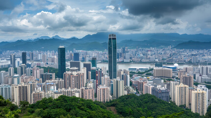 Naklejka premium Aerial view of dense urban skyline with skyscraper, river and mountain backdrop moody clouds