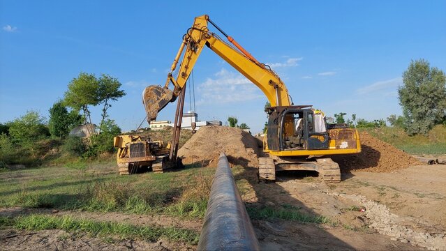 Heavy Duty Excavator and Pipelayer Working on Industrial Pipeline Construction