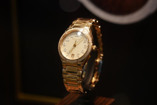 A luxury Patek Philippe gold watch with diamond bezel.