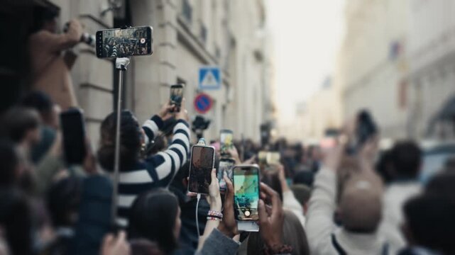 Large crowd of fans filming a parade with their smartphones
