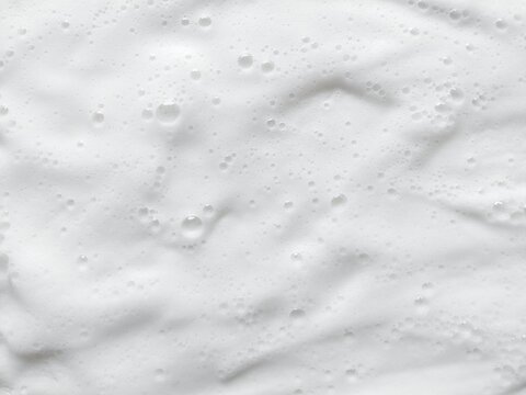 Abstract white soap foam texture with light fluffy bubbles background. Fresh shampoo lather foam backdrop for hygiene concept.