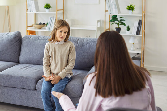 Child speaking with trust to psychologist during home counseling session, speech therapy and supportive development consultation. Boy sitting on sofa to talk with therapist about feelings, emotions