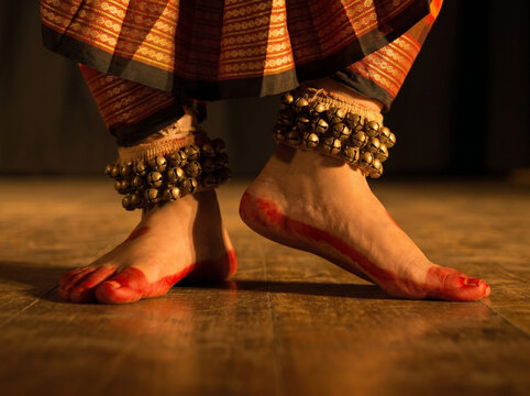 indian classical dance bharatanatyam feet with ghungroo performing on stage with warm dramatic lighting and cultural expression