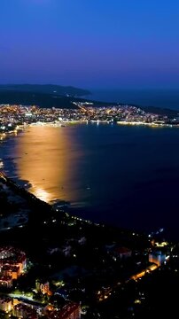 Vertical video. Gelendzhik, Russia. Night view of Gelendzhikskaya Bay. Fatty Mys. Night panorama of the city. Black Sea. Drone footage. Rich colors
