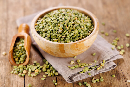 dry green split peas in a wooden bowl on a rustic table