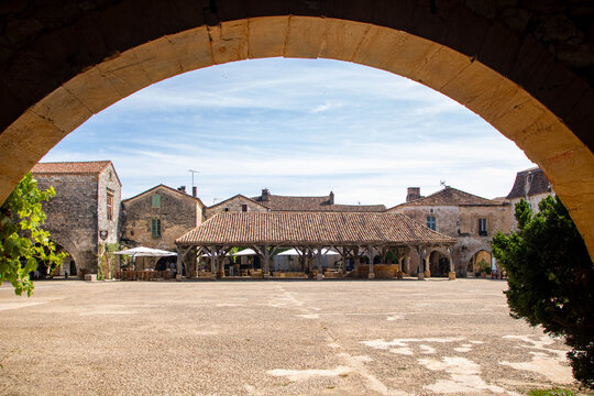 View of Monpazier medieval square framed by a historic stone arch