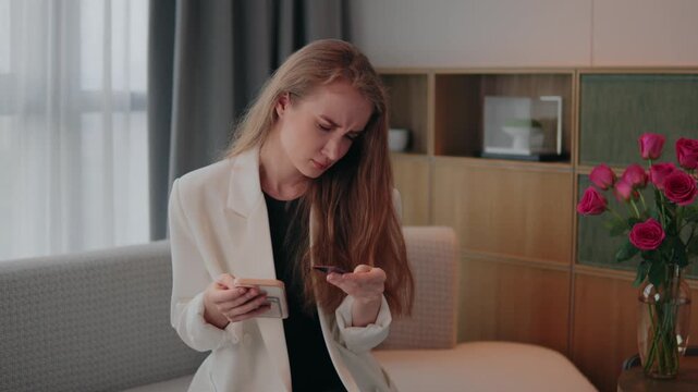 woman on a sofa holding a smartphone and credit card, frustrated by a failed online payment or insufficient funds while trying to complete a mobile purchase at home, credit card smartphone on sofa
