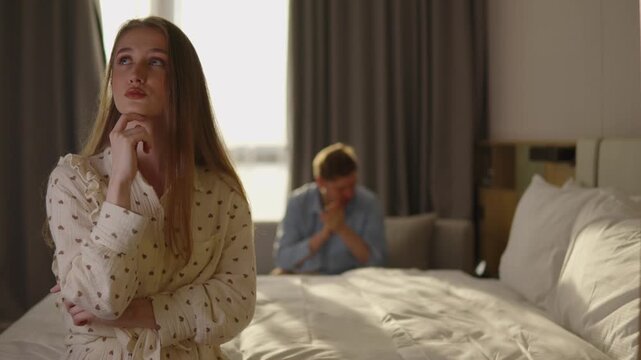 Upset woman struggling with emotions after relationship argument, man in background begging forgiveness, concept of regret, guilt, emotional healing, and difficult reconciliation moment