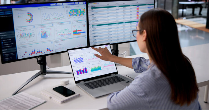 Young Female Data Analyst Reviews Hospital Spreadsheet On Laptop