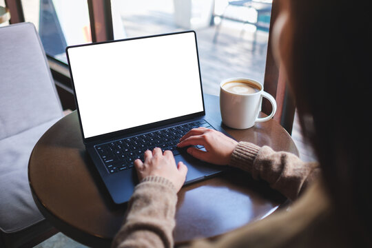 Mockup image of a woman working on laptop computer with blank white desktop screen in cafe