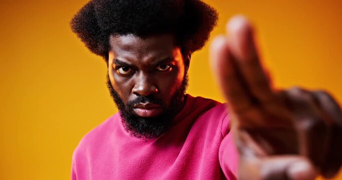 Man gesturing stop with hand against yellow background.
