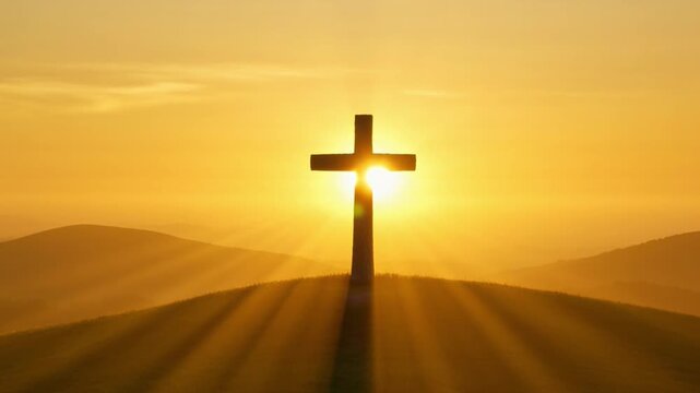 A golden cross silhouette stands on a hill as sun rays shine through in a peaceful sunset sky.
