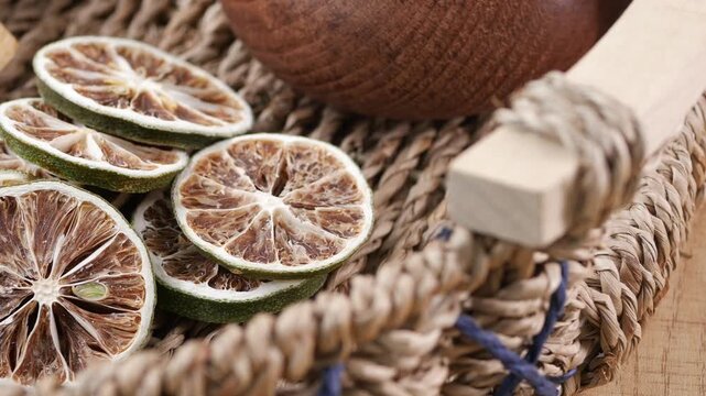 Dried limes in a woven basket with wooden bowl on table