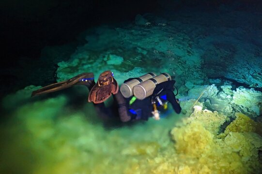 Scuba diver and halocline in the underwater cave. Halocline - optical effect of mixing fresh and sea water. Scuba diving in the cave. Extreme underwater exploration.