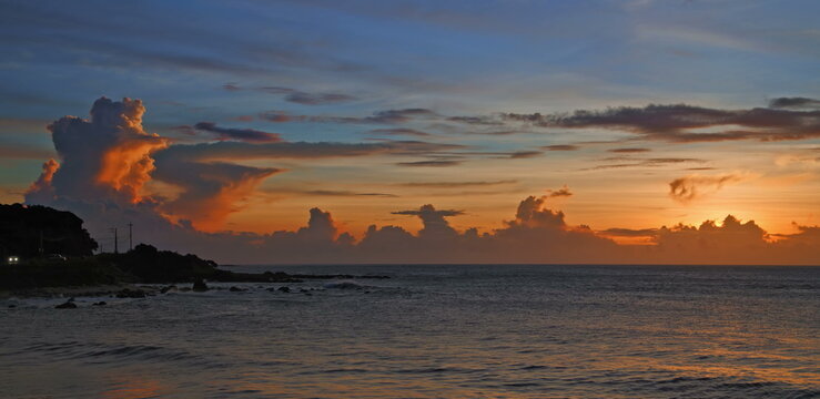Golden sun rising over the calm ocean horizon with soft orange clouds