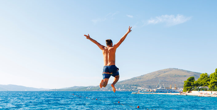 man jumping into the sea in croatia with freedom and success concept