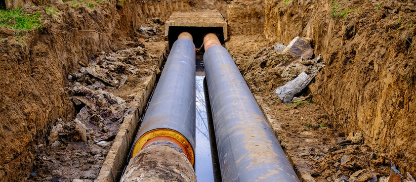 Repair and replacement of underground heating pipeline with insulated pipes in trench. Concept of rising energy costs, heating system modernization