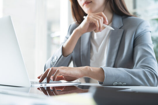 Businesswoman focus working at office using laptop with digital tablet on desk, corporate business concept
