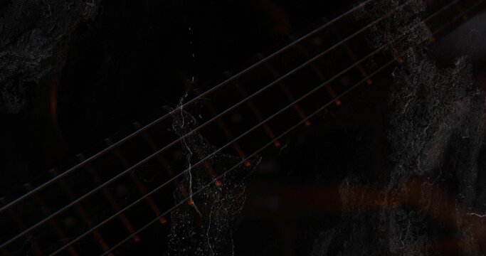 Highlighting guitar neck close-up in dark room, six strings frets dot inlays grunge texture