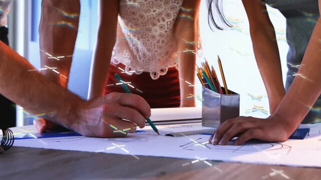 Design team leaning refining plans left drawing with green pencil middle pointing overlaying light