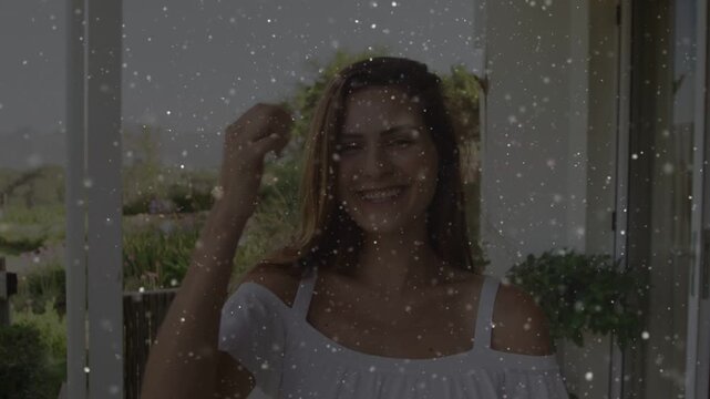 Vertical video: Smiling woman touching hair on balcony, reacting to camera, white off-shoulder top