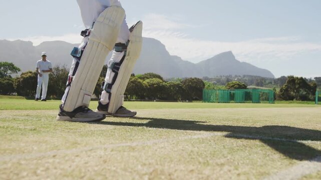 Batsman advancing on sunny cricket pitch, colored trail signaling delivery, bat blocking red ball