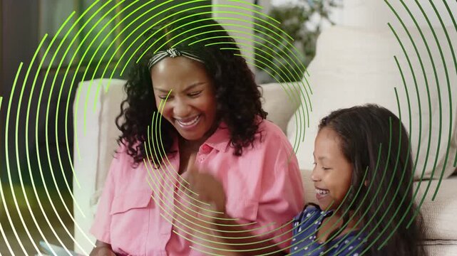 Mother pointing to book and guiding education, child high-fiving, green rings sweeping across frame