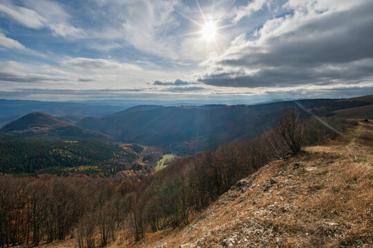 View of Kozi chrbat mountain ridge with autumn forests and rolling hills under a bright sun in Mostenica, Banska Bystrica Region, Slovakia.