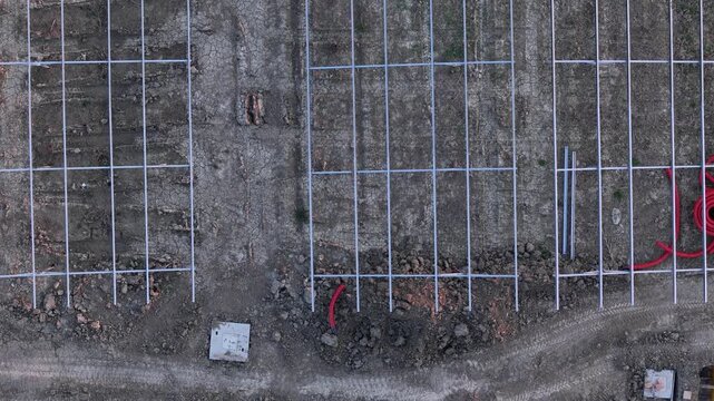 Drone footage captures the ongoing construction of a large solar power plant, showing metal support structures and electrical conduits being laid out on the ground