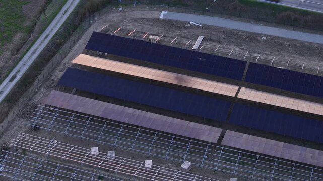 Drone footage captures the ongoing development of a large solar power plant with rows of photovoltaic panels and mounting structures