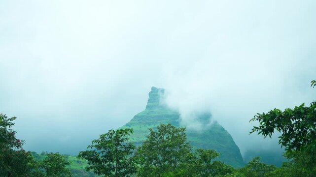 4K Landscape shot of clouds surrounding the green Sahyadri hills during the monsoon season as seen from Maharashtra, India. Scenic view of Western Ghats during the rain. Natural monsoon background.