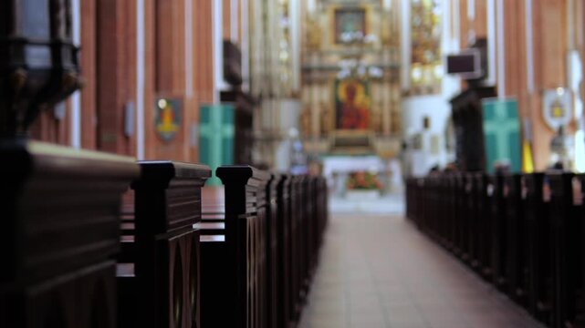 Empty church interior with wooden pews lining the central aisle leading towards a brightly lit, out of focus altar, creating a peaceful and spiritual atmosphere for worship and prayer