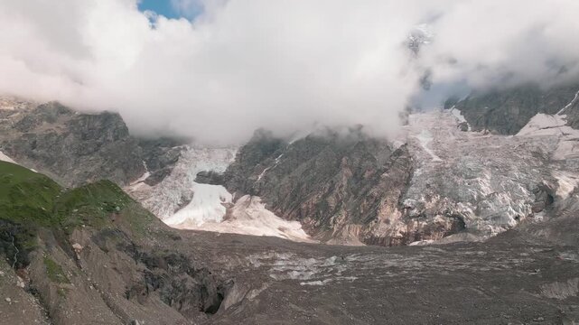 Aerial panning view Shkhara Glacier base by Mount Shkhara. Massive ice flow, rocky moraine near Ushguli. Source Enguri River, Upper Svaneti, Greater Caucasus Mountains, Georgia