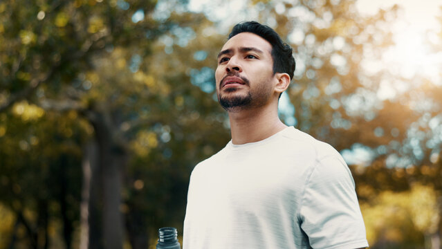 Man, fitness and thinking with water at park, serious and tired after workout or training in morning. Outdoor, athlete and person with drink in nature, reflection and cool down on break and low angle