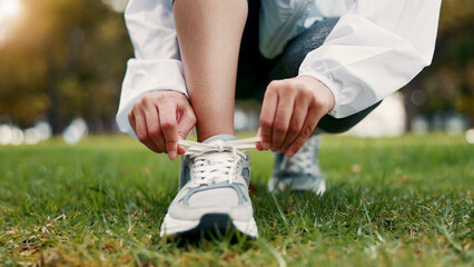 Obraz premium Person, hands and tying with shoes on grass field for fitness, workout preparation or run in nature. Active, runner or getting ready with sneakers or laces for outdoor exercise or training in park