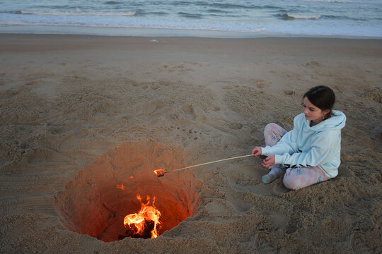Young girl roasting marshmallows at beach fire Cape Hatteras Nat